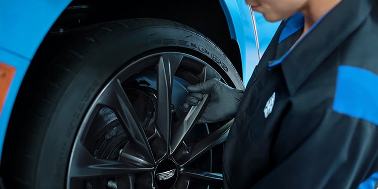 Cadillac Technician Installing a New Wheel on a Vehicle