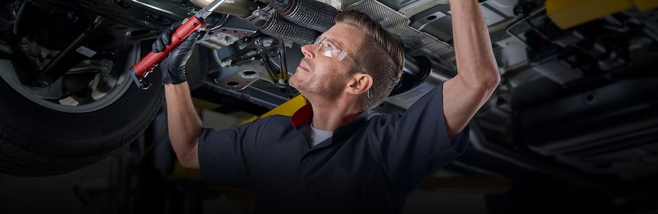 Cadillac Certified Service technician working on the underside of a vehicle