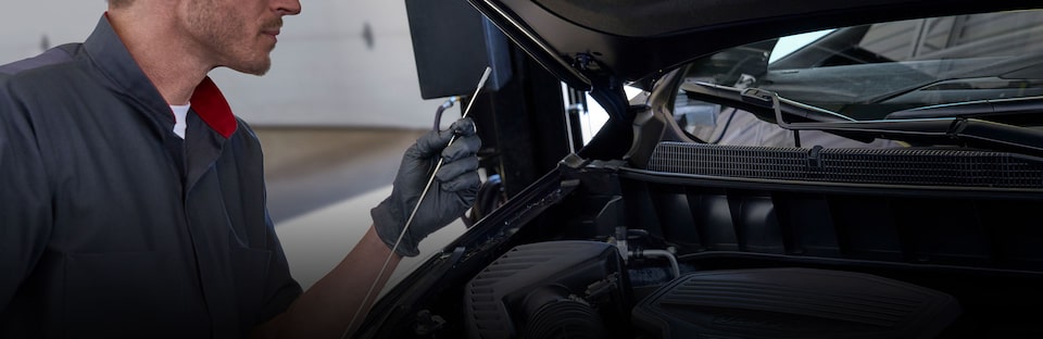 Cadillac Certified Service technician checking a vehicle’s oil