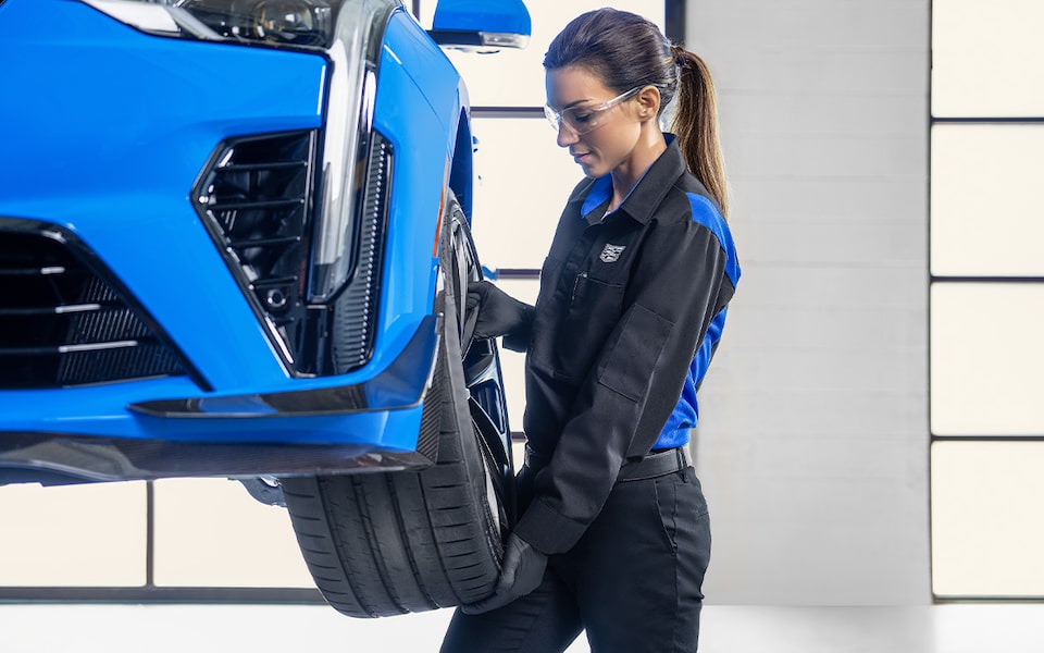 Cadillac Technician Standing in Front of a Cadillac Vehicle Inspecting a Sheet of Vehicle Information