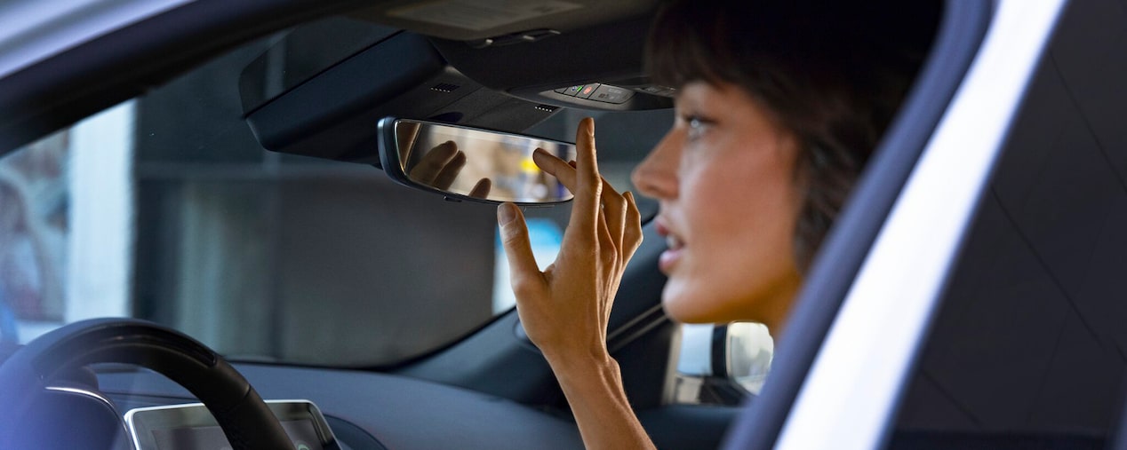 Close-up of a Woman Pressing the OnStar Button Near the Rear View Mirror in a Cadillac