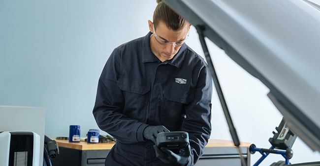 Cadillac Technician Inspecting Tool Standing Next to a Vehicle