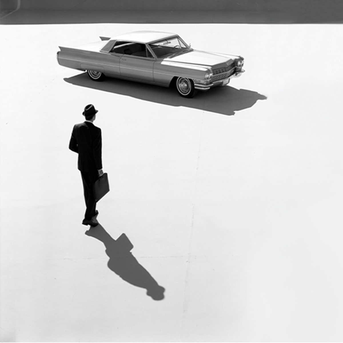 Black & White Overview of a Business Man Walking Towards a 1964 Cadillac Series 62 Coupe