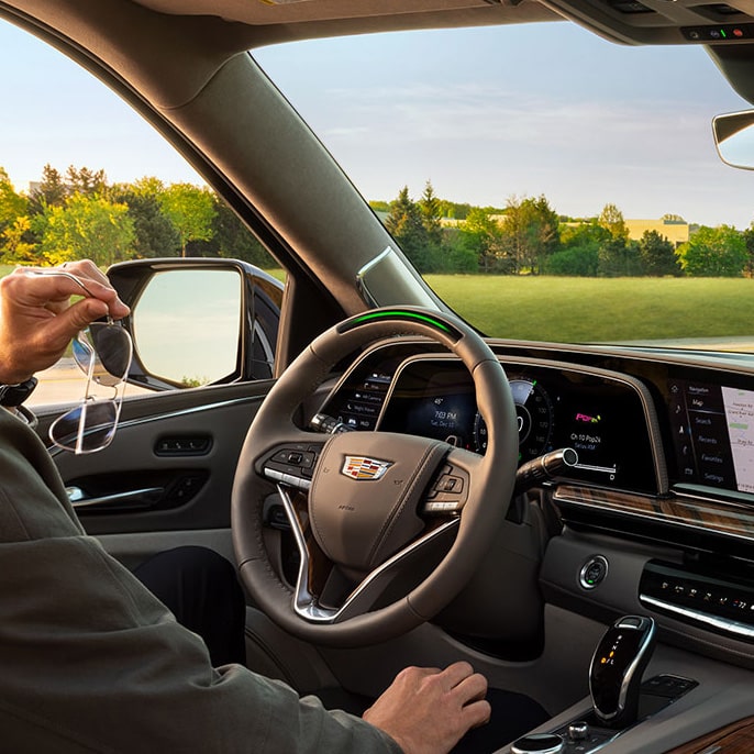 A Man Holding Sunglasses While Sitting in a Cadillac Vehicle Driver's Seat