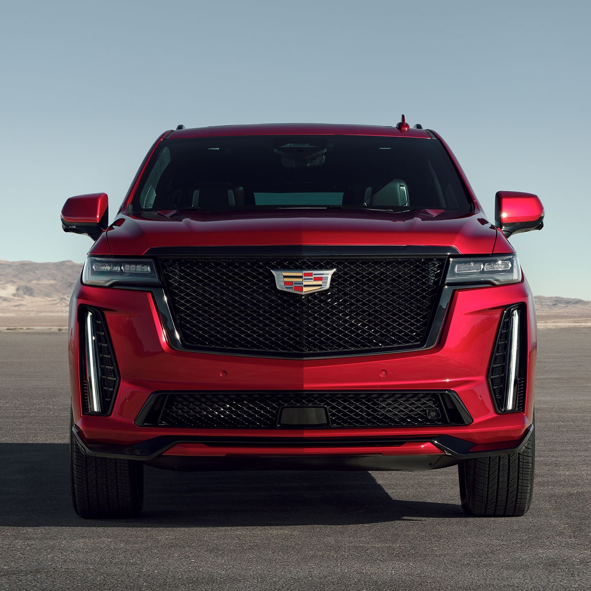 Front View of a Red Cadillac Escalade Parked By the Mountains