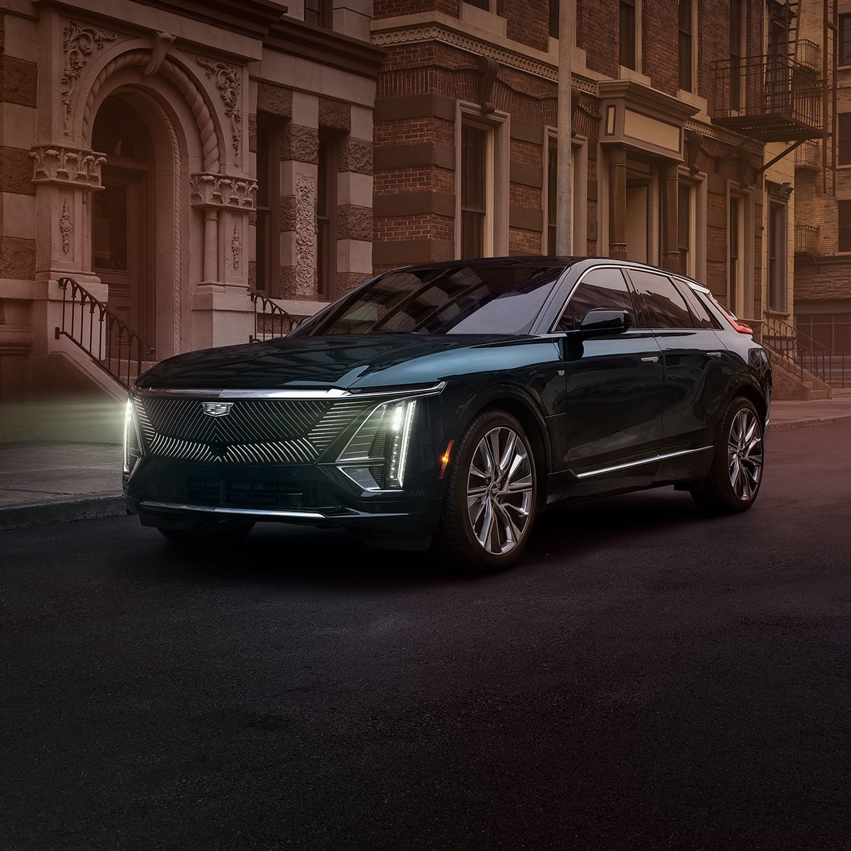 A Cadillac LYRIQ Drives Through a City at Dusk