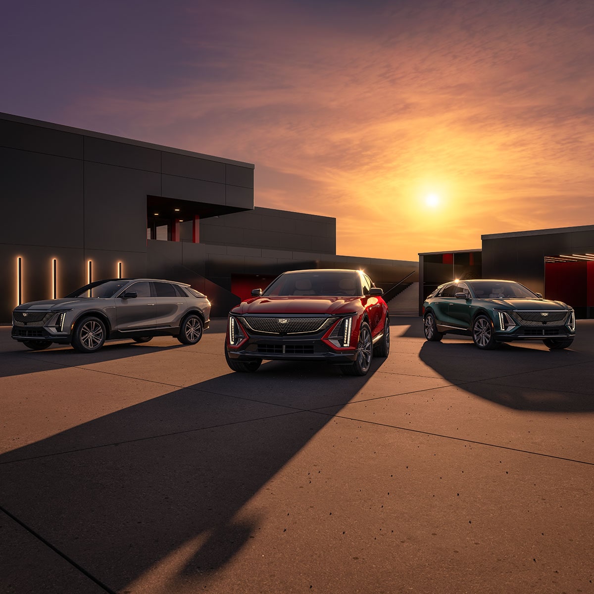 Two Cadillac LYRIQs Parked on the Drive of a Luxurious Home During Sunset