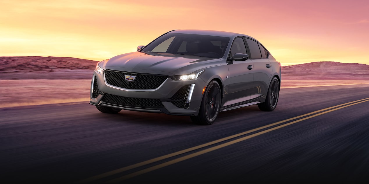 The 2024 Cadillac CT5 Driving Down a Road During Sunset