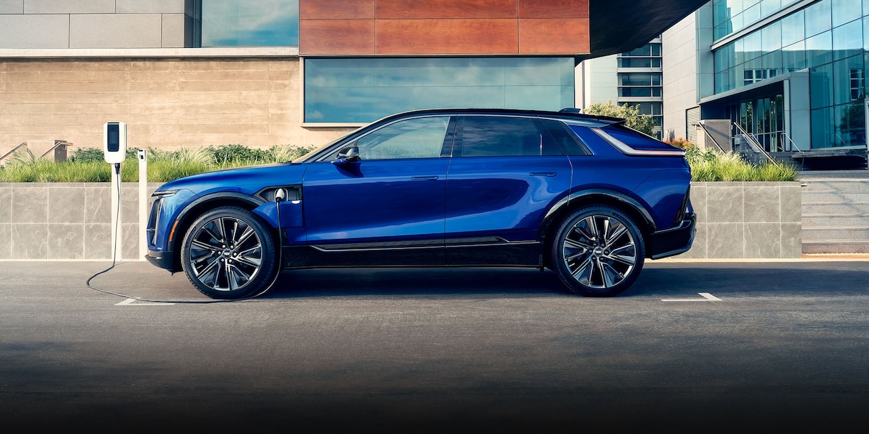 A Side Profile of a Blue 2024 Cadillac LYRIQ Charging Outside of a Building